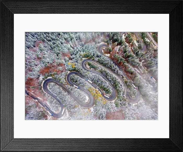 Framed Print : Aerial view of a winding mountain road passing through a fir trees forest. Winter with snow Framed Print : Aerial view of a winding mountain road passing through a fir trees forest. Winter with snow