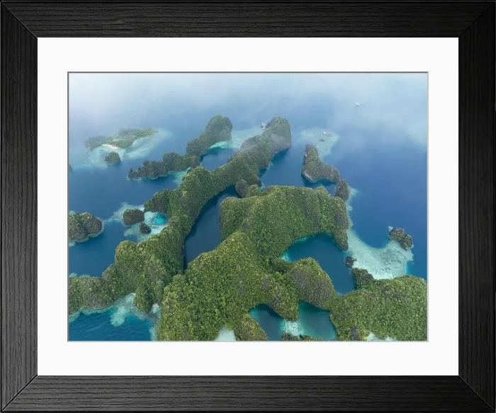 Framed Print : Coral reefs surround the rugged limestone islands that rise from Raja Ampat's seascape. This remote part of Indonesia has high marine biodiversity
