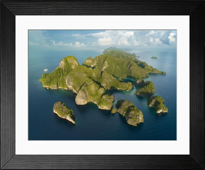 Framed Print : Coral reefs surround the rugged limestone islands that rise from Raja Ampat's seascape. This remote part of Indonesia has high marine biodiversity