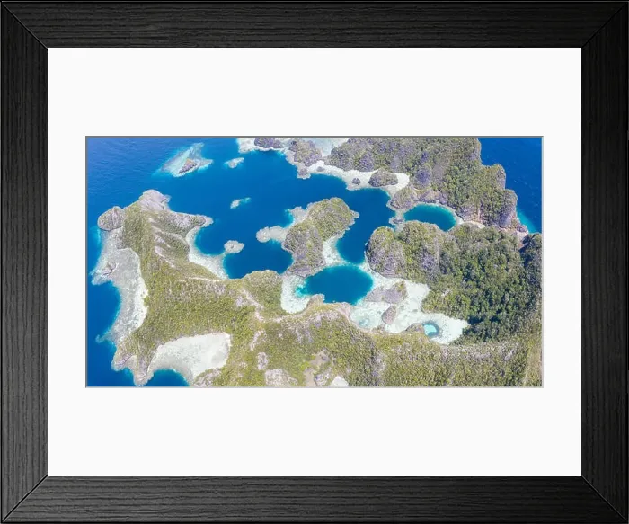 Framed Print : Highly eroded limestone islands rise from the beautiful, tropical seascape in Raja Ampat, Indonesia. This remote region is known for its biodiversity Framed Print : Highly eroded limestone islands rise from the beautiful, tropical seascape in Raja Ampat, Indonesia. This remote region is known for its biodiversity