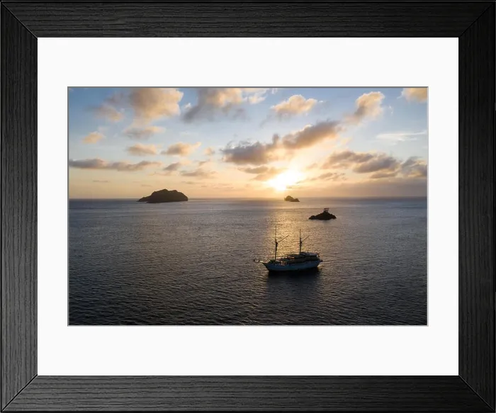 Framed Print : A peaceful sunset silhouettes limestone islands and a Pinisi schooner in Raja Ampat, Indonesia. This area harbors extraordinary marine biodiversity Framed Print : A peaceful sunset silhouettes limestone islands and a Pinisi schooner in Raja Ampat, Indonesia. This area harbors extraordinary marine biodiversity