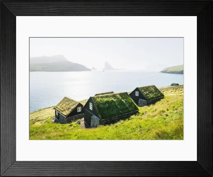 Framed Print : Picturesque view of tradicional faroese grass-covered houses in the village Bour. Drangarnir and Tindholmur sea stacks on background Framed Print : Picturesque view of tradicional faroese grass-covered houses in the village Bour. Drangarnir and Tindholmur sea stacks on background
