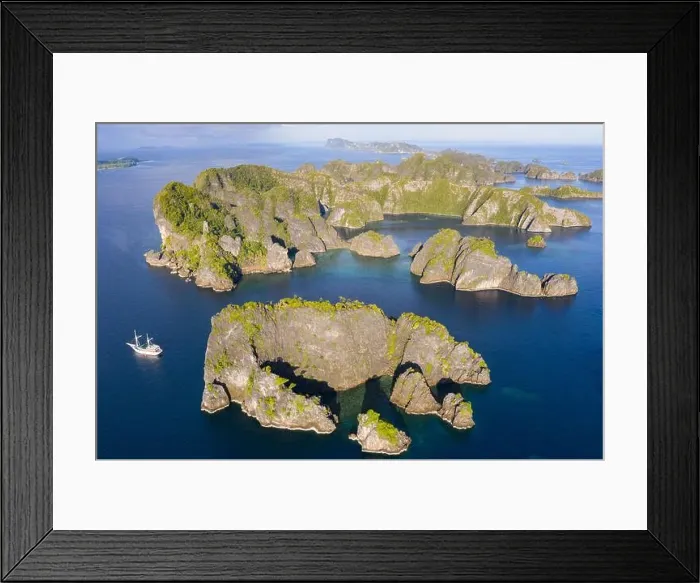 Framed Print : Rock islands, composed of limestone, rise from the tropical seascape in Raja Ampat, Indonesia. These islands are ancient uplifted coral reefs Framed Print : Rock islands, composed of limestone, rise from the tropical seascape in Raja Ampat, Indonesia. These islands are ancient uplifted coral reefs