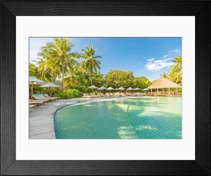 Framed Print : Summer outdoor tourism landscape. Luxurious beach resort with swimming pool and beach chairs or loungers under umbrellas with palm trees and blue sky Framed Print : Summer outdoor tourism landscape. Luxurious beach resort with swimming pool and beach chairs or loungers under umbrellas with palm trees and blue sky