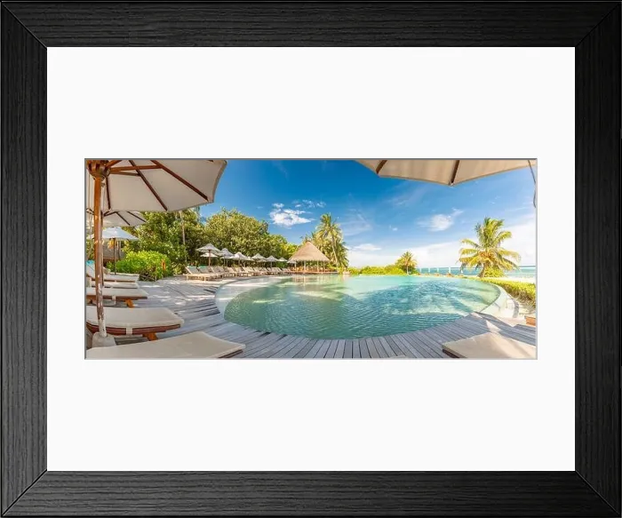 Framed Print : Summer outdoor tourism landscape. Luxurious beach resort with swimming pool and beach chairs or loungers under umbrellas with palm trees and blue sky Framed Print : Summer outdoor tourism landscape. Luxurious beach resort with swimming pool and beach chairs or loungers under umbrellas with palm trees and blue sky