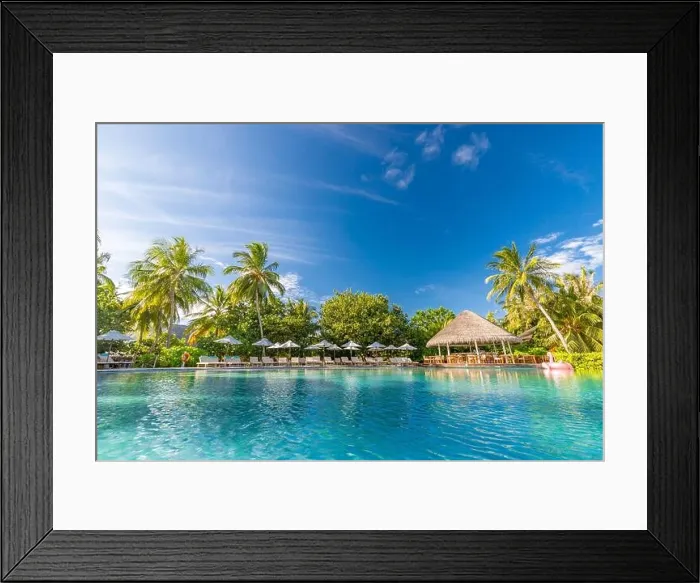 Framed Print : Summer outdoor tourism landscape. Luxurious beach resort with swimming pool and beach chairs or loungers under umbrellas with palm trees and blue sky Framed Print : Summer outdoor tourism landscape. Luxurious beach resort with swimming pool and beach chairs or loungers under umbrellas with palm trees and blue sky