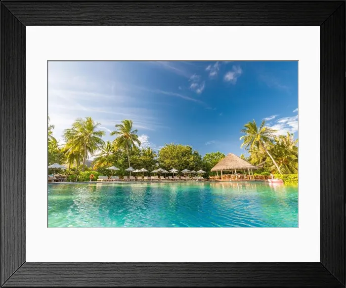 Framed Print : Summer outdoor tourism landscape. Luxurious beach resort with swimming pool and beach chairs or loungers under umbrellas with palm trees and blue sky Framed Print : Summer outdoor tourism landscape. Luxurious beach resort with swimming pool and beach chairs or loungers under umbrellas with palm trees and blue sky
