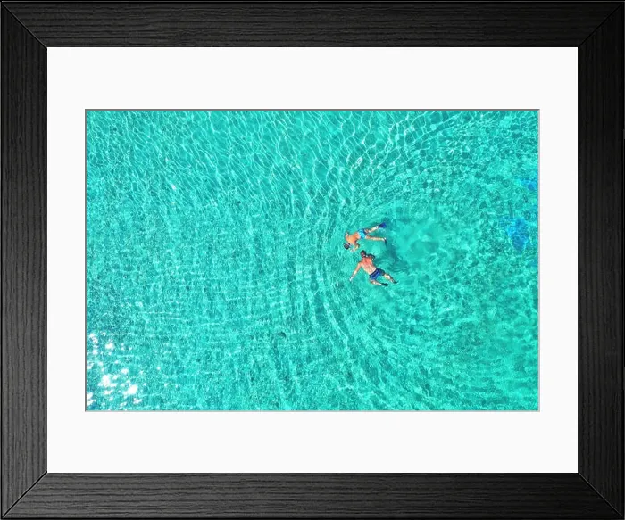 Framed Print : Father and son snorkels through tropical, turquoise waters, aerial view Framed Print : Father and son snorkels through tropical, turquoise waters, aerial view