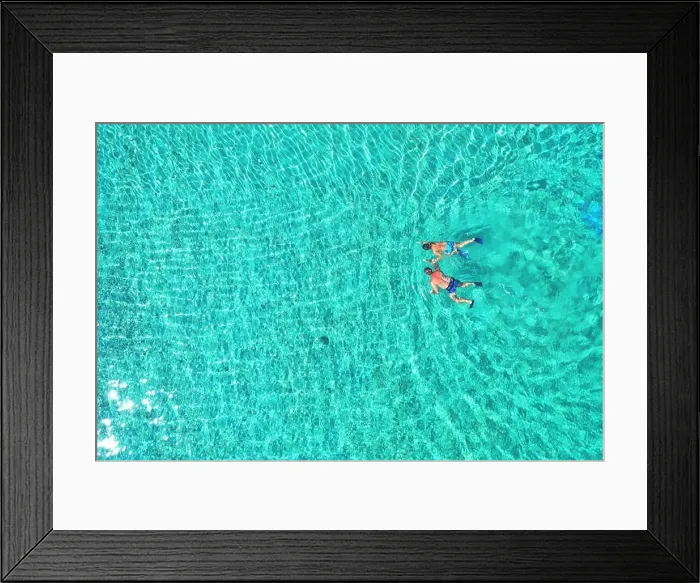 Framed Print : Father and son snorkels through tropical, turquoise waters, aerial view Framed Print : Father and son snorkels through tropical, turquoise waters, aerial view