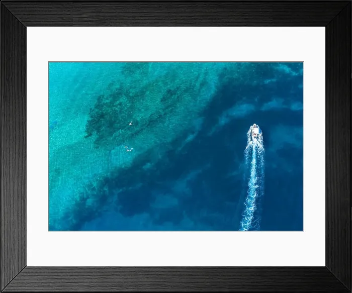 Framed Print : Speed boat near father and son snorkels through tropical, turquoise waters, aerial view Framed Print : Speed boat near father and son snorkels through tropical, turquoise waters, aerial view