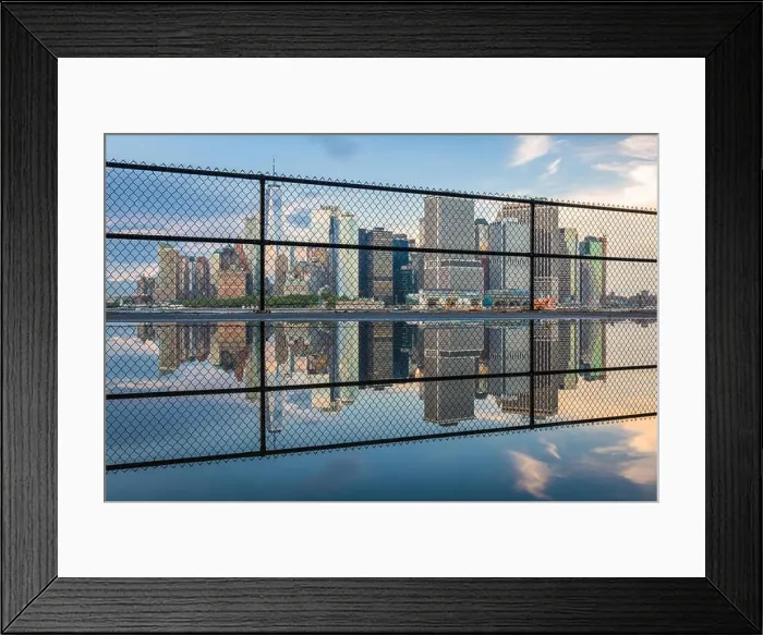 Framed Print : New York, New York, USA city skyline of Lower Manhattan on the New York harbor through fencing Framed Print : New York, New York, USA city skyline of Lower Manhattan on the New York harbor through fencing