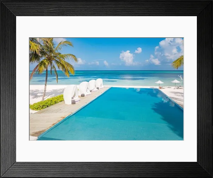 Framed Print : Outdoor tourism landscape. Luxurious beach resort with swimming pool and beach chairs or loungers under umbrellas with palm trees and blue sky. Exotic Framed Print : Outdoor tourism landscape. Luxurious beach resort with swimming pool and beach chairs or loungers under umbrellas with palm trees and blue sky. Exotic