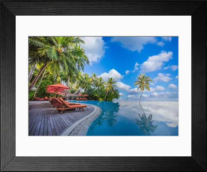 Framed Print : Luxurious beach resort with swimming pool seaside beach chairs or loungers under umbrellas with palm trees and blue sky. Summer travel hotel vacation Framed Print : Luxurious beach resort with swimming pool seaside beach chairs or loungers under umbrellas with palm trees and blue sky. Summer travel hotel vacation