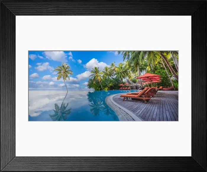 Framed Print : Luxurious beach resort with swimming pool seaside beach chairs or loungers under umbrellas with palm trees and blue sky. Summer travel hotel vacation Framed Print : Luxurious beach resort with swimming pool seaside beach chairs or loungers under umbrellas with palm trees and blue sky. Summer travel hotel vacation