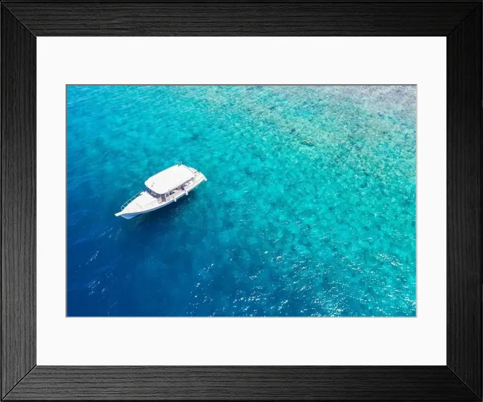 Framed Print : Small yacht sailing in tropical sea over coral reef in Indian ocean lagoon. Exotic island landscape, aerial view, tranquil nature scenic Framed Print : Small yacht sailing in tropical sea over coral reef in Indian ocean lagoon. Exotic island landscape, aerial view, tranquil nature scenic