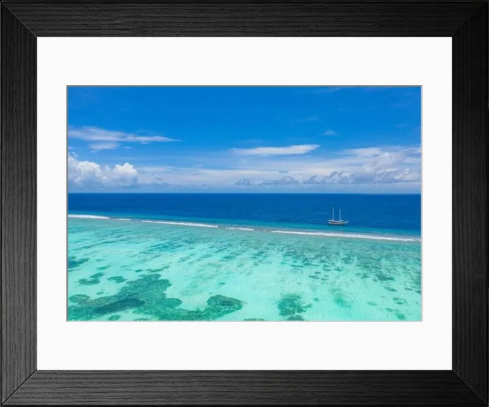 Framed Print : Small yacht sailing in tropical sea over coral reef in Indian ocean lagoon. Exotic island landscape, aerial view, tranquil nature scenic Framed Print : Small yacht sailing in tropical sea over coral reef in Indian ocean lagoon. Exotic island landscape, aerial view, tranquil nature scenic