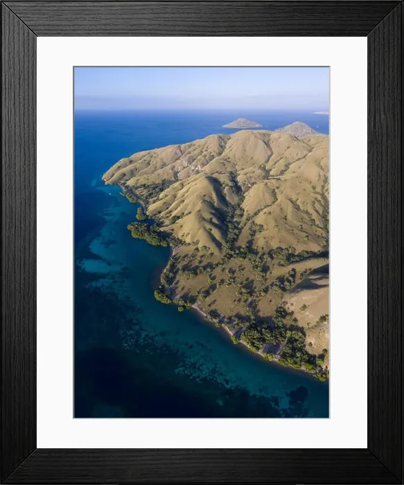 Framed Print : Seen from a bird's eye view, the blue Pacific Ocean surrounds the rugged island of Komodo in Indonesia. This tropical area is known for its diversity Framed Print : Seen from a bird's eye view, the blue Pacific Ocean surrounds the rugged island of Komodo in Indonesia. This tropical area is known for its diversity