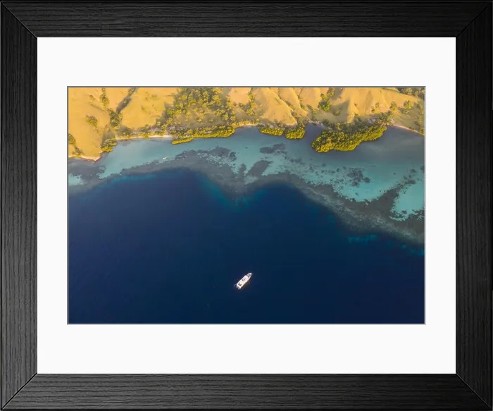 Framed Print : Seen from a bird's eye view, an idyllic island is surrounded by a healthy coral reef in Komodo National Park, Indonesia Framed Print : Seen from a bird's eye view, an idyllic island is surrounded by a healthy coral reef in Komodo National Park, Indonesia