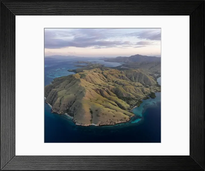 Framed Print : Seen from a bird's eye view, the blue Pacific Ocean surrounds the rugged island of Komodo in Indonesia. This tropical area is known for its diversity Framed Print : Seen from a bird's eye view, the blue Pacific Ocean surrounds the rugged island of Komodo in Indonesia. This tropical area is known for its diversity