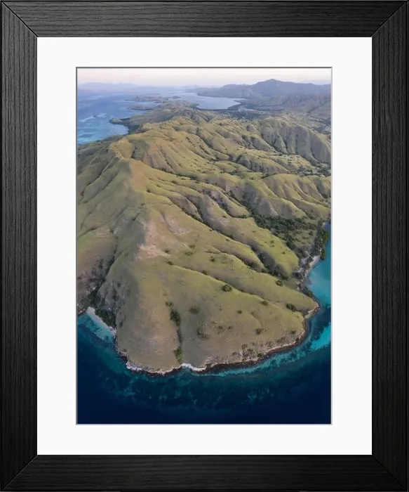 Framed Print : Seen from a bird's eye view, the blue Pacific Ocean surrounds the rugged island of Komodo in Indonesia. This tropical area is known for its diversity Framed Print : Seen from a bird's eye view, the blue Pacific Ocean surrounds the rugged island of Komodo in Indonesia. This tropical area is known for its diversity