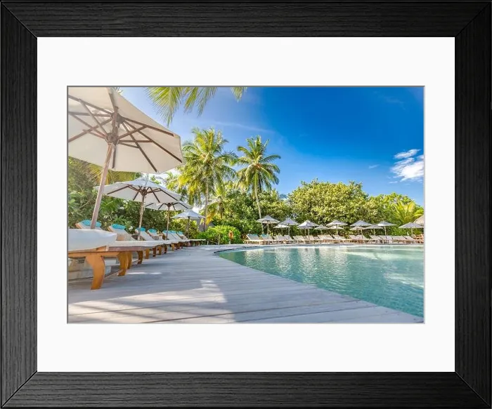 Framed Print : Outdoor summer tourism landscape. Luxurious beach resort with swimming pool and beach chairs or loungers under umbrellas with palm trees and blue sky Framed Print : Outdoor summer tourism landscape. Luxurious beach resort with swimming pool and beach chairs or loungers under umbrellas with palm trees and blue sky