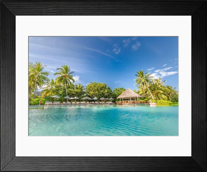 Framed Print : Outdoor summer tourism landscape. Luxurious beach resort with swimming pool and beach chairs or loungers under umbrellas with palm trees and blue sky Framed Print : Outdoor summer tourism landscape. Luxurious beach resort with swimming pool and beach chairs or loungers under umbrellas with palm trees and blue sky