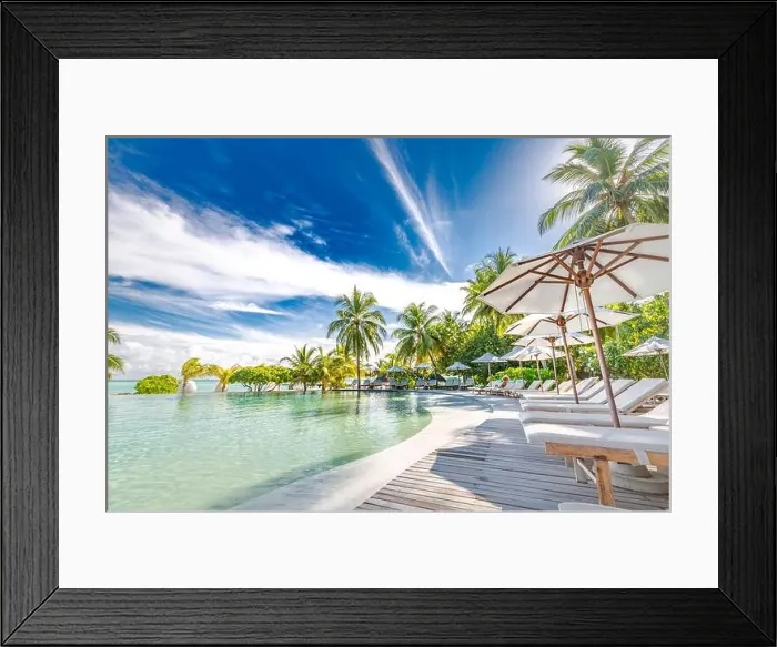 Framed Print : Outdoor summer tourism landscape. Luxurious beach resort with swimming pool and beach chairs or loungers under umbrellas with palm trees and blue sky Framed Print : Outdoor summer tourism landscape. Luxurious beach resort with swimming pool and beach chairs or loungers under umbrellas with palm trees and blue sky