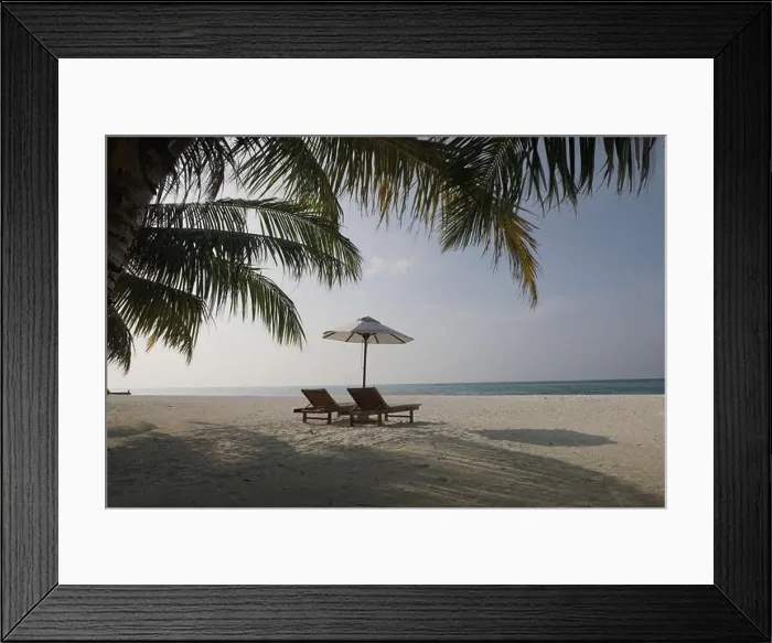 Framed Print : Unedited beach landscape with chairs and umbrella under palm leaves and soft blue sky. Soft colors summer landscape, vacation travel holiday, for edit Framed Print : Unedited beach landscape with chairs and umbrella under palm leaves and soft blue sky. Soft colors summer landscape, vacation travel holiday, for edit