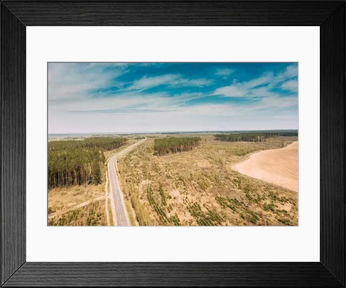Framed Print : Aerial view of highway road through deforestation area landscape. Green pine forest in deforestation zone. Top view of field and forest landscape in Framed Print : Aerial view of highway road through deforestation area landscape. Green pine forest in deforestation zone. Top view of field and forest landscape in