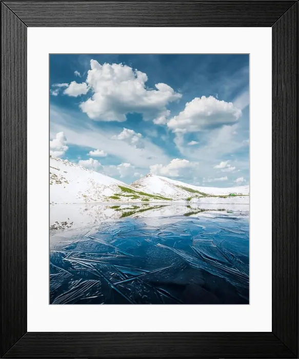 Framed Print : Frozen mountain lake with blue ice and cracks on the surface. Picturesque winter landscape with snowy hills under a blue cloudy sky Framed Print : Frozen mountain lake with blue ice and cracks on the surface. Picturesque winter landscape with snowy hills under a blue cloudy sky