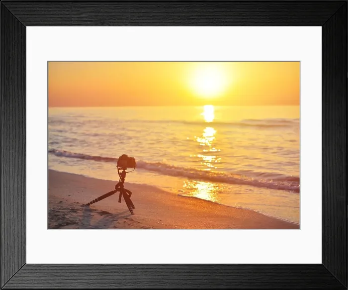 Framed Print : Sunrise over the sea coast. Fireball of the sun above the horizon in a colorful orange sky. DSLR camera on a tripod in the foreground Framed Print : Sunrise over the sea coast. Fireball of the sun above the horizon in a colorful orange sky. DSLR camera on a tripod in the foreground