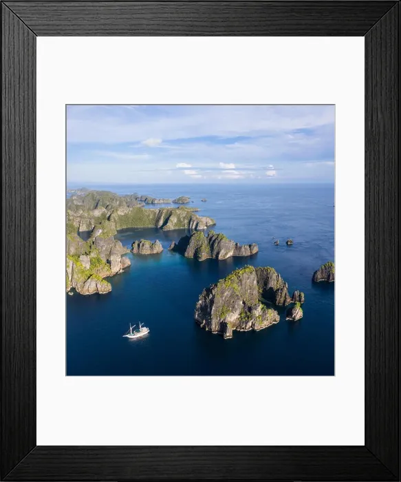 Framed Print : Remote limestone islands rise from the stunning seascape in Raja Ampat, Indonesia. This diverse region is known as the heart of the Coral Triangle Framed Print : Remote limestone islands rise from the stunning seascape in Raja Ampat, Indonesia. This diverse region is known as the heart of the Coral Triangle