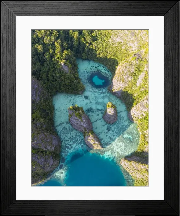 Framed Print : Seen from above, remote islands are surrounded by coral reefs in Raja Ampat, Indonesia. This region is known as the heart of the Coral Triangle Framed Print : Seen from above, remote islands are surrounded by coral reefs in Raja Ampat, Indonesia. This region is known as the heart of the Coral Triangle