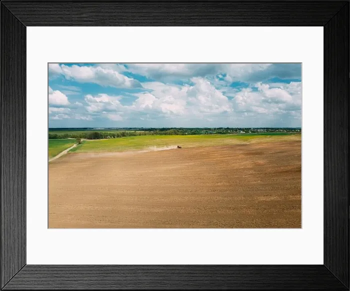 Framed Print : Red Tractor Plowing Field In Spring Season. Beginning Of Agricultural Spring Season. Cultivator Pulled By A Tractor In Countryside Field. Aerial View