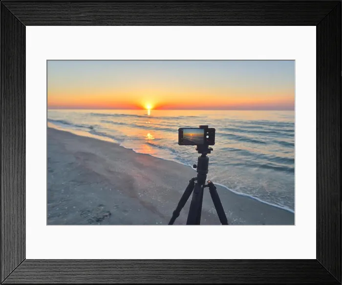 Framed Print : Sunrise over the sea coast. Fireball of the sun above the horizon in a colorful orange sky. Smartphone camera on a tripod in the foreground Framed Print : Sunrise over the sea coast. Fireball of the sun above the horizon in a colorful orange sky. Smartphone camera on a tripod in the foreground