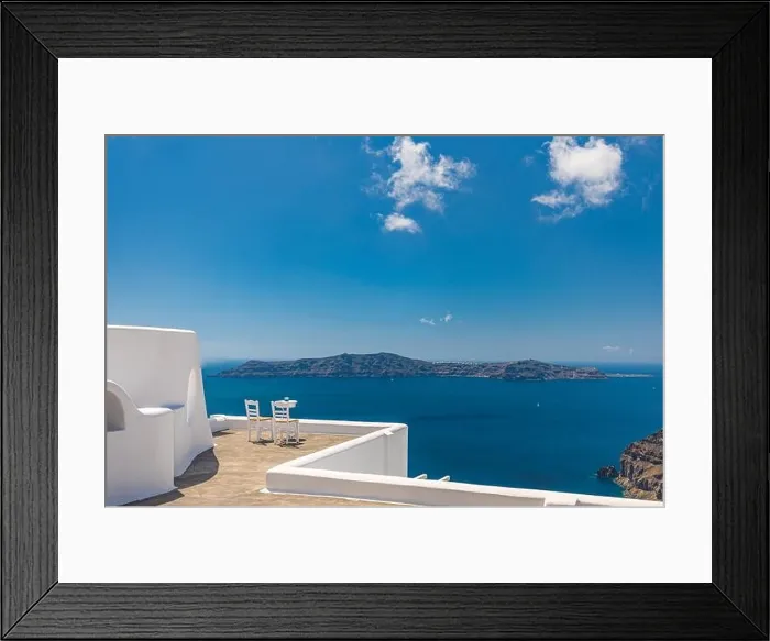 Framed Print : White architecture on Santorini island, Greece. Outdoor restaurant under a fantastic landscape, chairs for couple. Romantic view, summer vacation Framed Print : White architecture on Santorini island, Greece. Outdoor restaurant under a fantastic landscape, chairs for couple. Romantic view, summer vacation