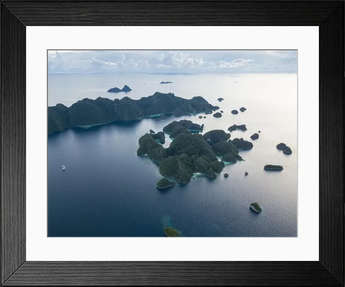 Framed Print : A bird's eye view shows dramatic limestone islands rising from the peaceful, tropical seascape in Raja Ampat, Indonesia Framed Print : A bird's eye view shows dramatic limestone islands rising from the peaceful, tropical seascape in Raja Ampat, Indonesia