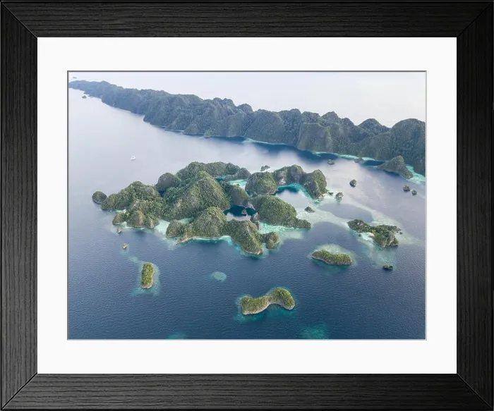 Framed Print : Beautiful limestone islands rise from the calm seas of Raja Ampat, Indonesia. This remote region is known for its extraordinary marine biodiversity Framed Print : Beautiful limestone islands rise from the calm seas of Raja Ampat, Indonesia. This remote region is known for its extraordinary marine biodiversity