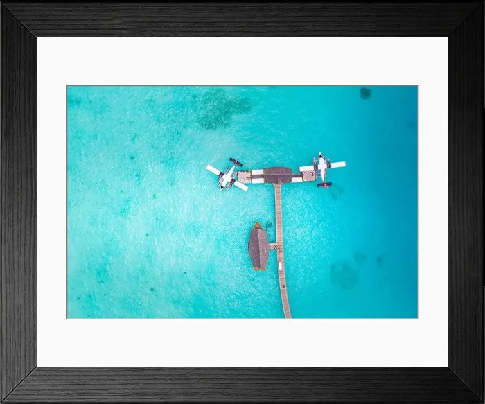 Framed Print : Beautiful aerial view of Maldives jetty seaplane top view with wooden boat Dhoni and tropical beach, jetty over wonderful blue sea. Luxury travel