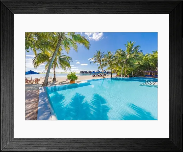 Framed Print : Summer tourism landscape. Luxurious beach resort with swimming pool and beach chairs or loungers under umbrellas with palm trees and blue sky, relax Framed Print : Summer tourism landscape. Luxurious beach resort with swimming pool and beach chairs or loungers under umbrellas with palm trees and blue sky, relax