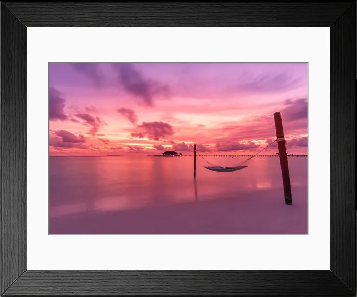 Framed Print : Dramatic sunset sky in tropical island beach. Swing or hammock over water. Purple pink sky clouds, artistic sunrise landscape, coastline Framed Print : Dramatic sunset sky in tropical island beach. Swing or hammock over water. Purple pink sky clouds, artistic sunrise landscape, coastline