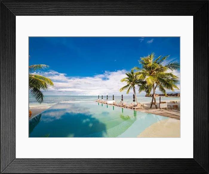 Framed Print : Outdoor tourism landscape. Luxurious beach resort with swimming pool and beach chairs or loungers under umbrellas with palm trees and blue sky. Summer Framed Print : Outdoor tourism landscape. Luxurious beach resort with swimming pool and beach chairs or loungers under umbrellas with palm trees and blue sky. Summer