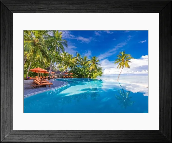 Framed Print : Outdoor tourism landscape. Luxurious beach resort with swimming pool and beach chairs or loungers under umbrellas with palm trees and blue sky. Summer Framed Print : Outdoor tourism landscape. Luxurious beach resort with swimming pool and beach chairs or loungers under umbrellas with palm trees and blue sky. Summer