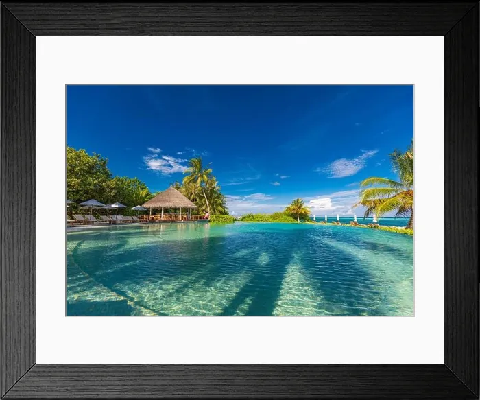 Framed Print : tourism landscape. Luxurious beach resort with swimming pool and beach chairs or loungers under umbrellas with palm trees and blue sky. Summer island Framed Print : tourism landscape. Luxurious beach resort with swimming pool and beach chairs or loungers under umbrellas with palm trees and blue sky. Summer island