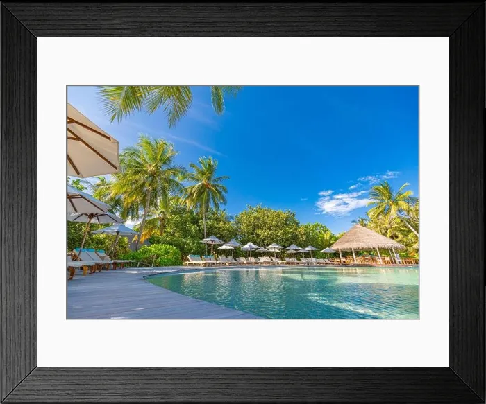 Framed Print : tourism landscape. Luxurious beach resort with swimming pool and beach chairs or loungers under umbrellas with palm trees and blue sky. Summer island Framed Print : tourism landscape. Luxurious beach resort with swimming pool and beach chairs or loungers under umbrellas with palm trees and blue sky. Summer island