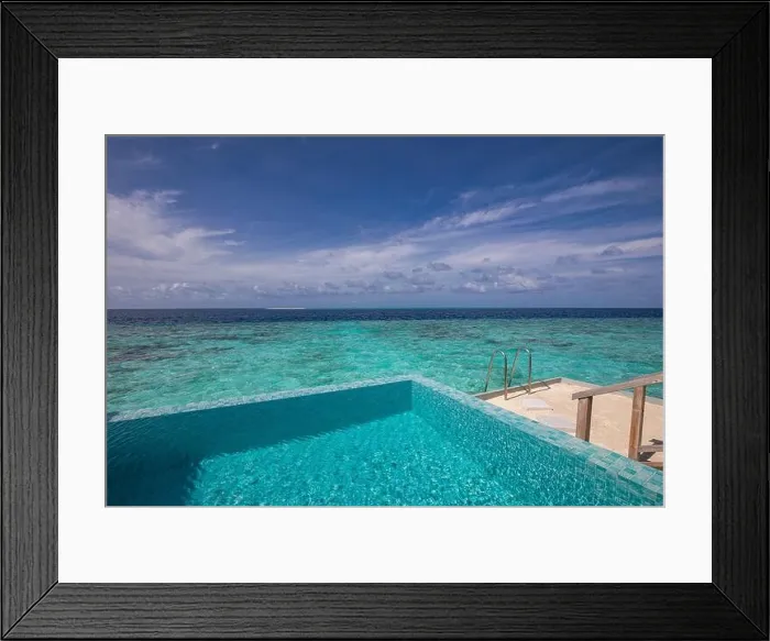 Framed Print : Luxurious beach resort with swimming pool and beach chairs or loungers under umbrellas with palm trees and blue sky. Summer travel and vacation scene Framed Print : Luxurious beach resort with swimming pool and beach chairs or loungers under umbrellas with palm trees and blue sky. Summer travel and vacation scene