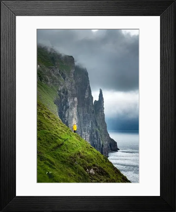 Framed Print : Tourist in yellow jacket looks at Witches Finger cliffs from Trollkonufingur viewpoint. Vagar island, Faroe Islands, Denmark Framed Print : Tourist in yellow jacket looks at Witches Finger cliffs from Trollkonufingur viewpoint. Vagar island, Faroe Islands, Denmark