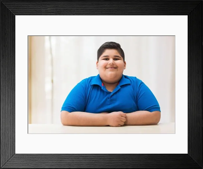 Framed Print : Portrait of a chubby boy sitting with his hands on the table. (Obesity) Framed Print : Portrait of a chubby boy sitting with his hands on the table. (Obesity)
