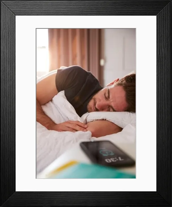Framed Print : Man Asleep In Bed With Mobile Phone On Bedside Table Framed Print : Man Asleep In Bed With Mobile Phone On Bedside Table