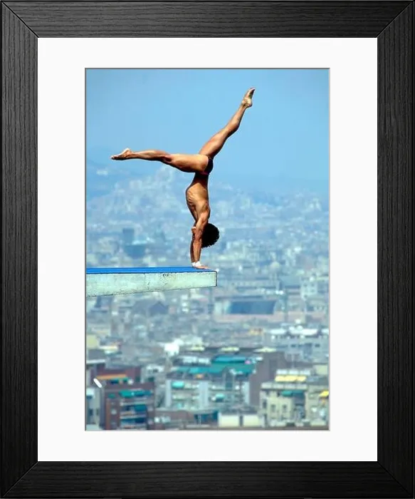 Framed Print : Barcelona, Spain: Male diver performs handstand on 10-meter platform at beginning of his dive, with the Barcelona skyline in the background Framed Print : Barcelona, Spain: Male diver performs handstand on 10-meter platform at beginning of his dive, with the Barcelona skyline in the background